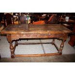 A large 18th Century rustic oak refectory table, the thick planked top raised on a carved frieze
