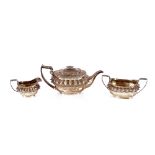 A George IV silver three piece teaset of baluster form, having raised foliate borders and scroll
