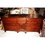 A large antique oak dresser base, fitted seven drawers around a central cupboard enclosed by a
