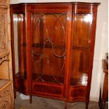 An Edwardian inlaid mahogany serpentine fronted display cabinet, enclosed by a glazed tracery