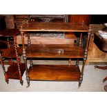A Victorian walnut three tier buffet, raised on turned baluster supports terminating in castors,