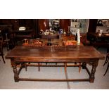 A large antique oak refectory dining table, the planked top raised on turned baluster supports