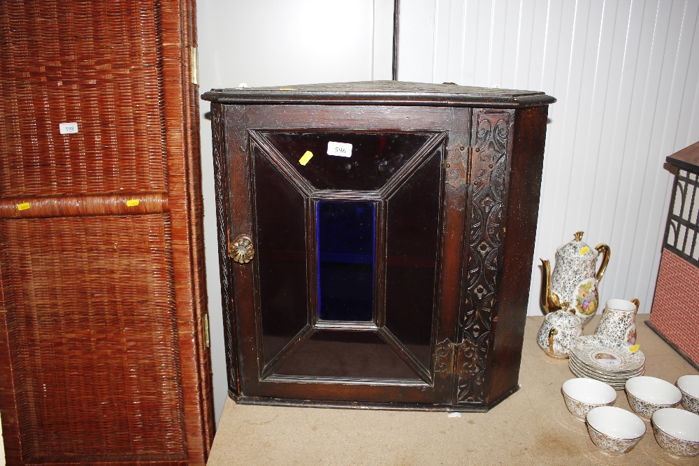 A carved wooden hanging corner cupboard enclosed b