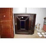 A carved wooden hanging corner cupboard enclosed b