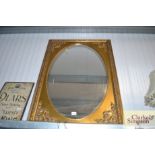 A large oval mirror contained in a large gilt fram