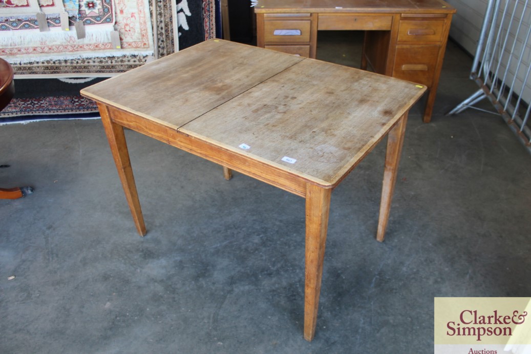 A teak extending dining table with one extra leaf