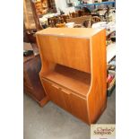 A teak drinks cabinet with full front raised on cu