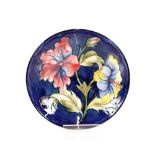 A Moorcroft bowl with floral decoration on blue gr