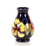 A Moorcroft Pottery baluster vase, leaf decoration on a deep blue ground, paper label to base "By