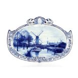 An oval Delft plaque, of cartouche shape decorated canal scene, 54cm x 39cm