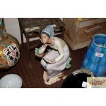 A Lladro figure depicting a seated girl reading a