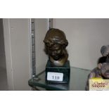 A small bronze bust of a boy on faux green marble