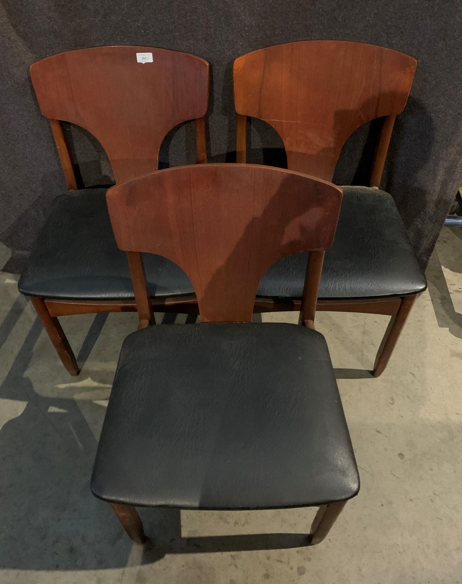 Three teak 1960s dining chairs with black PVC seats - [Please note - the upholstery in this lot