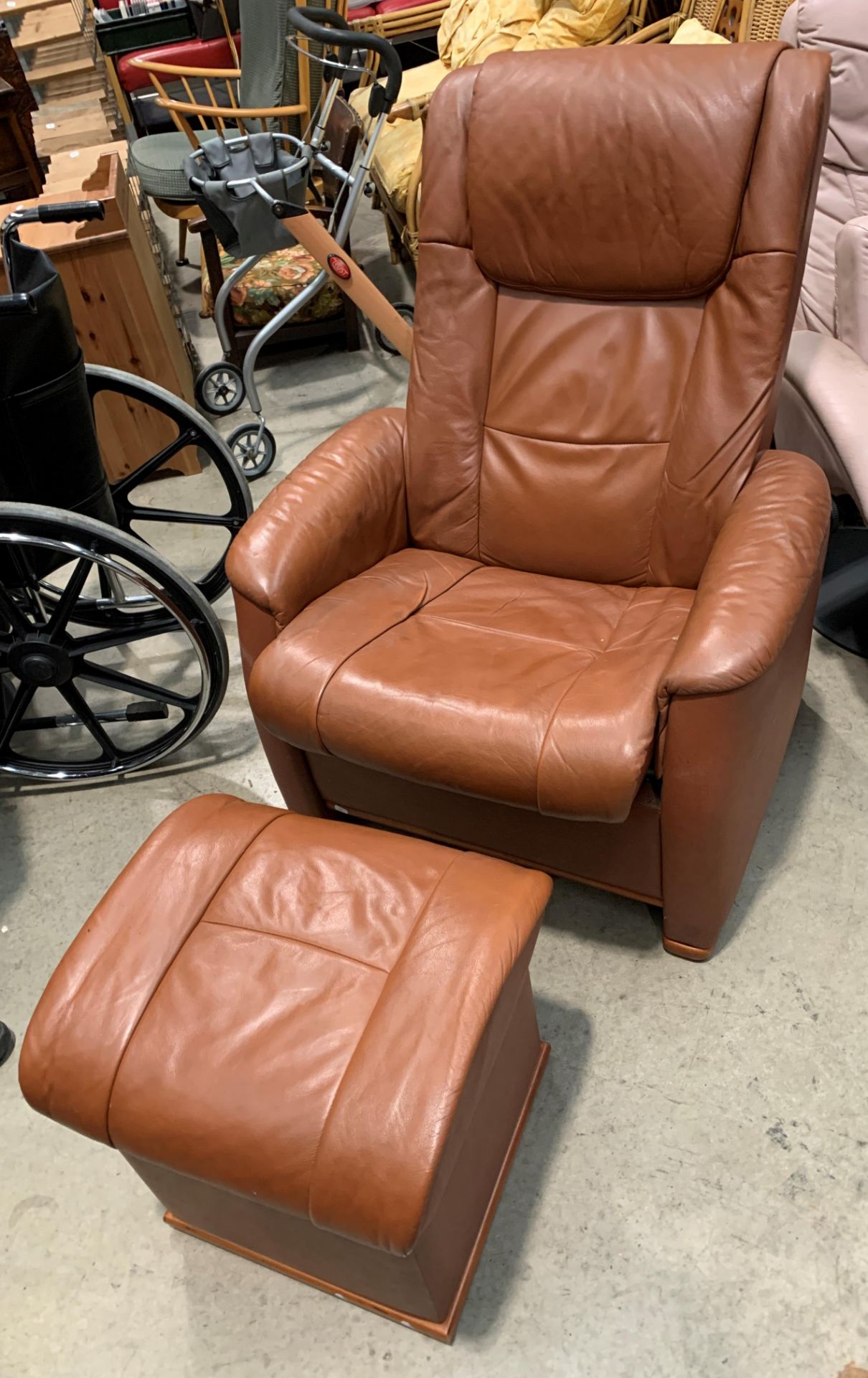 A medium brown reclining armchair with matching lift top stool/side table