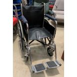 A chrome framed four wheel manual wheel chair with foot rests