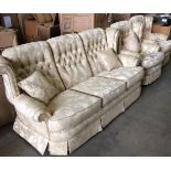 A beige and gold leaf patterned three piece suite comprising three seater settee and two armchairs