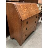 A 1930s oak bureau with fall flap over three drawers,