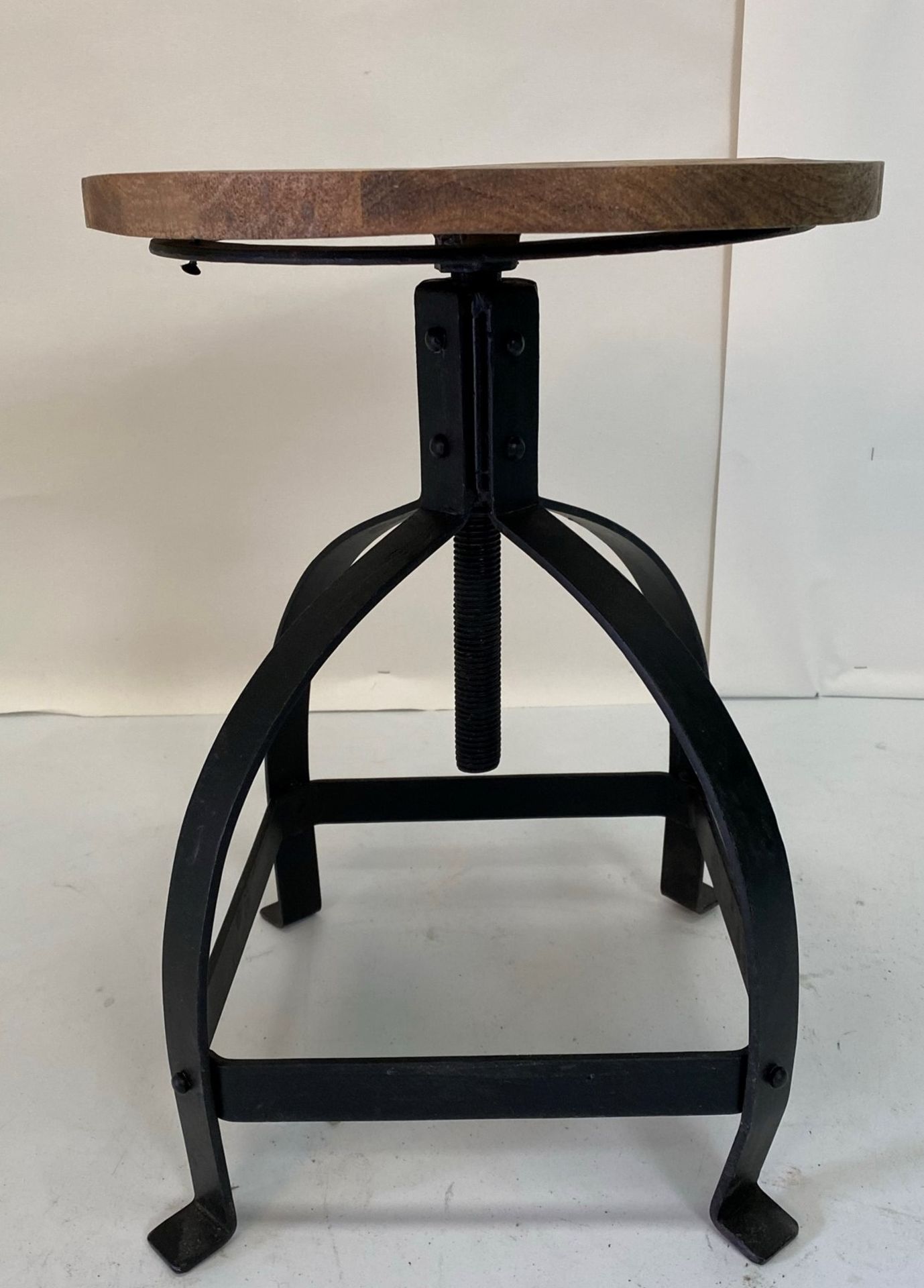 An Industrial low stool with wooden seat and black metal frame