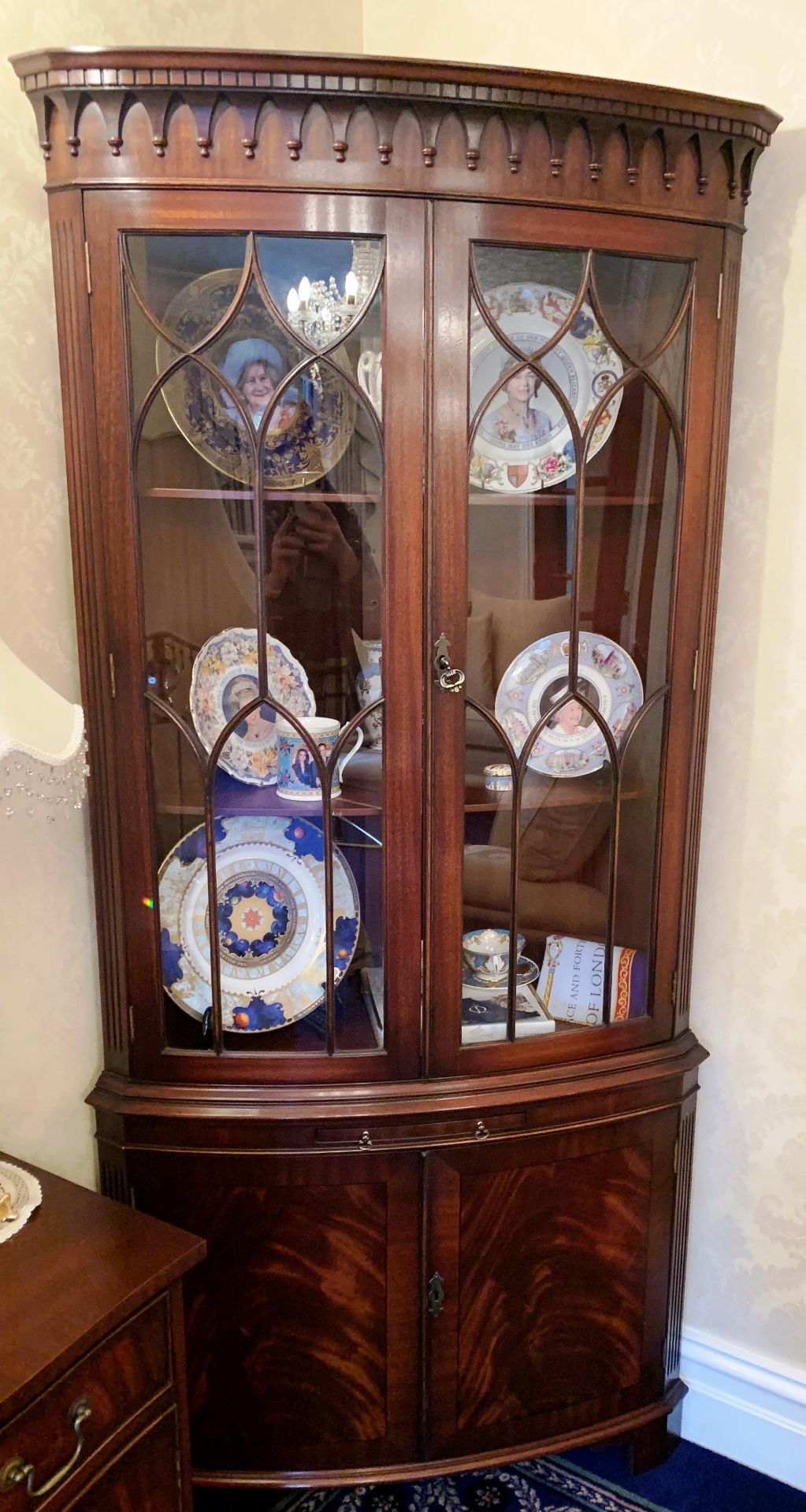 A tall curved front corner wall unit in dark mahogany finish with two glazed doors over slide two