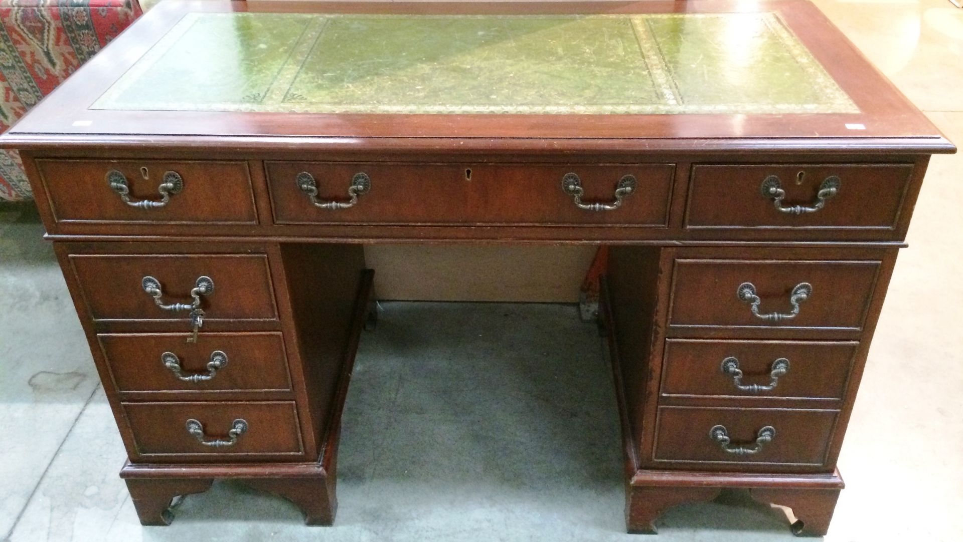 A mahogany finish reproduction eight drawer (one dummy two drawer) kneehole desk with green tooled