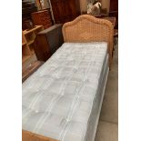 A blue patterned 3' single bed base and mattress with wicker headboard