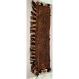 A rust with blue ground patterned wall hanging 32 x 123cm plus tassels