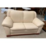 A cream leather two seater settee - slight nick to back left corner