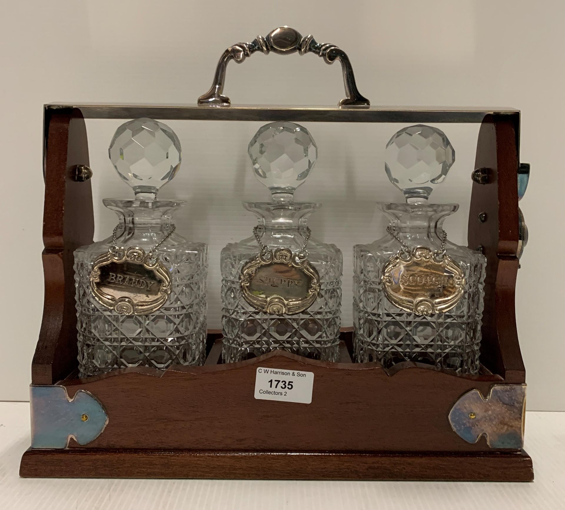 A wood framed Tantalus complete with three crystal glass decanters with silver coloured labels