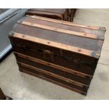 A wood and metal framed brown fibre dome top trunk 78 x 50 x 54cm high max with label Draw Co