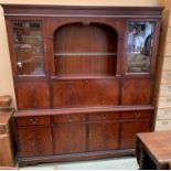 A large mahogany finish wall unit with two upper glazed doors flanking on open display section with