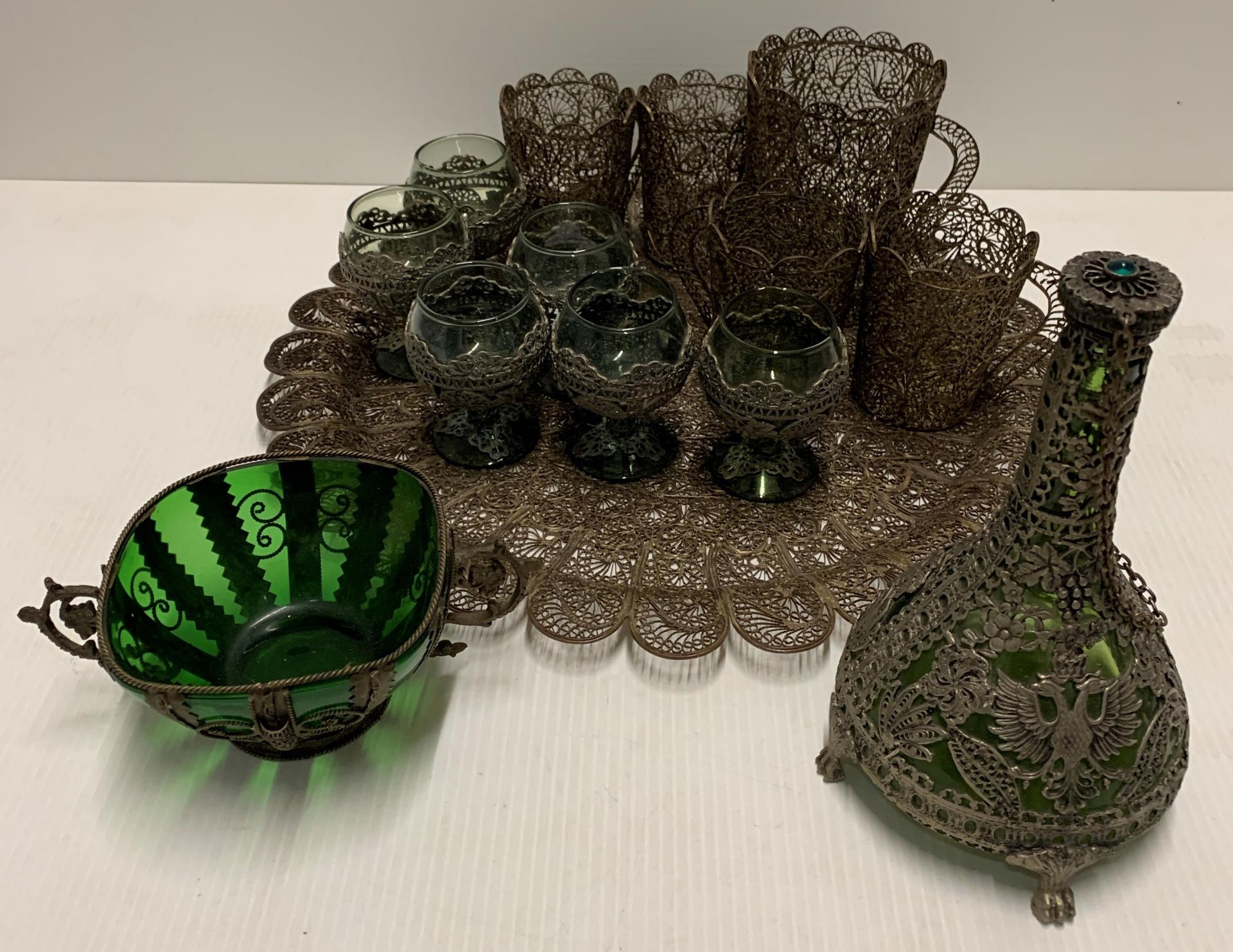 A wire work tray and contents small green/blue decanters and six wine glasses with wire detail,