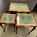 A nest of three mahogany finish coffee tables with green tooled leather finish tops with glass