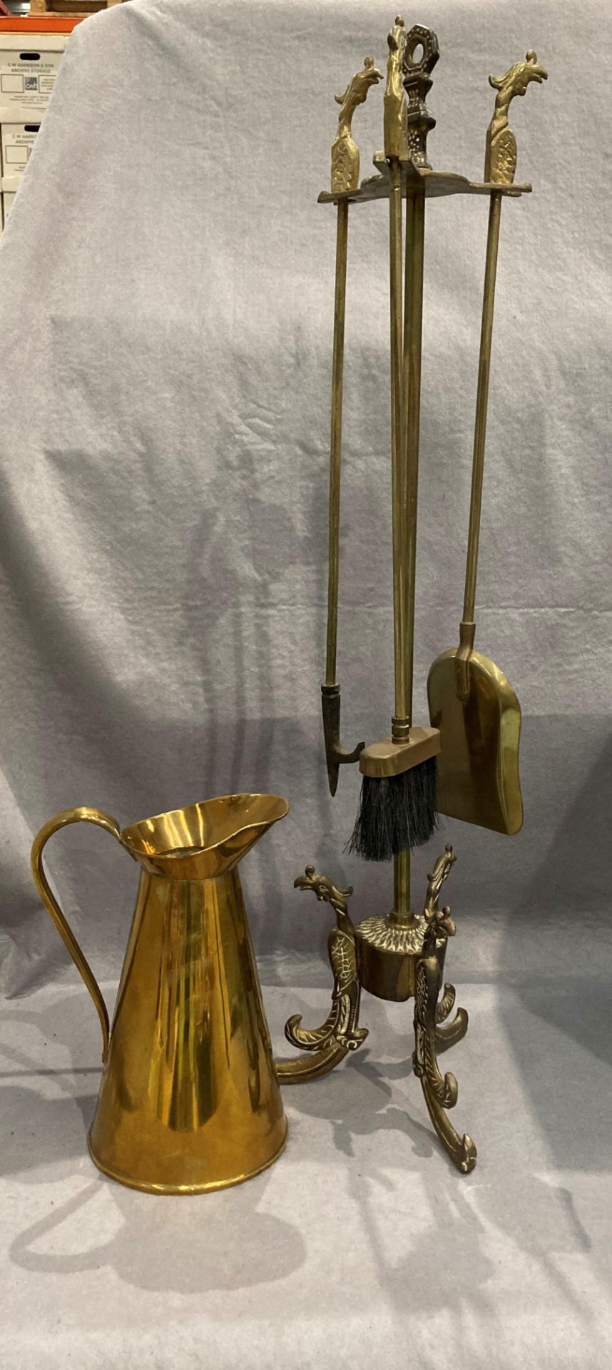 A decorative fireside stand fitted with three fireside implements and a brass jug (2)