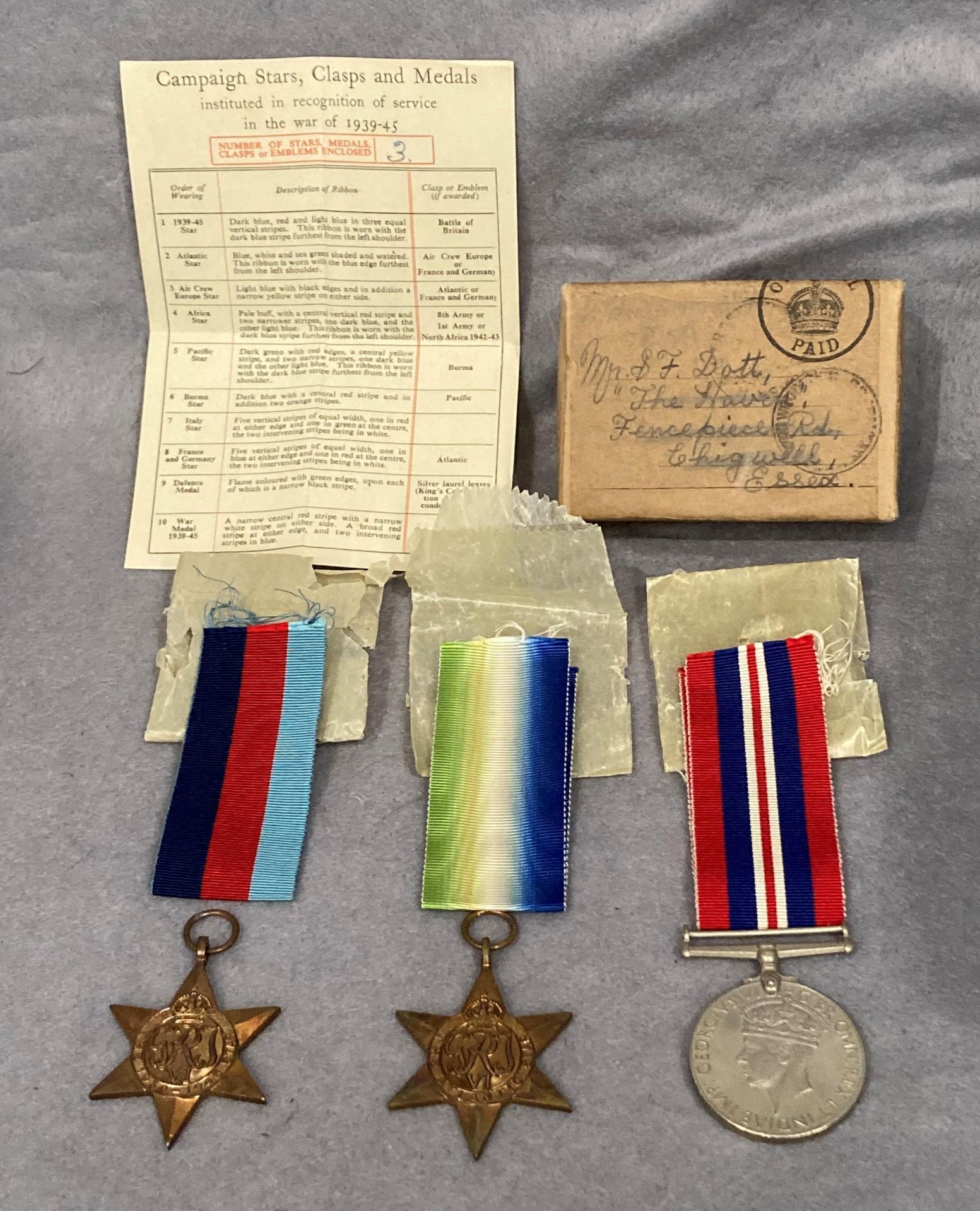 Three Second World War medals and ribbons in a box addressed to Mr. S.