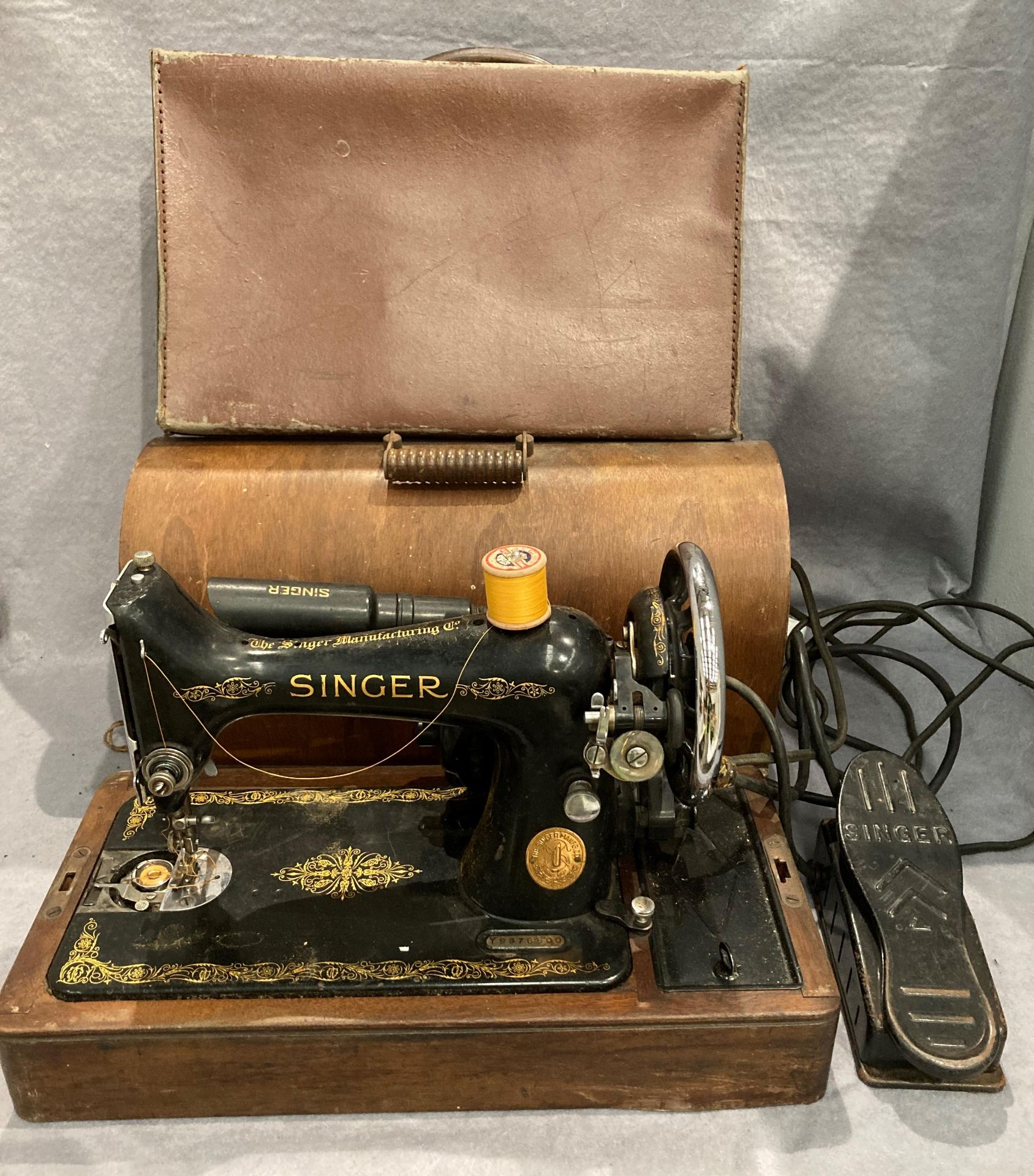 A Singer 240v portable sewing machine complete with foot pedal and a small brown fibre suitcase