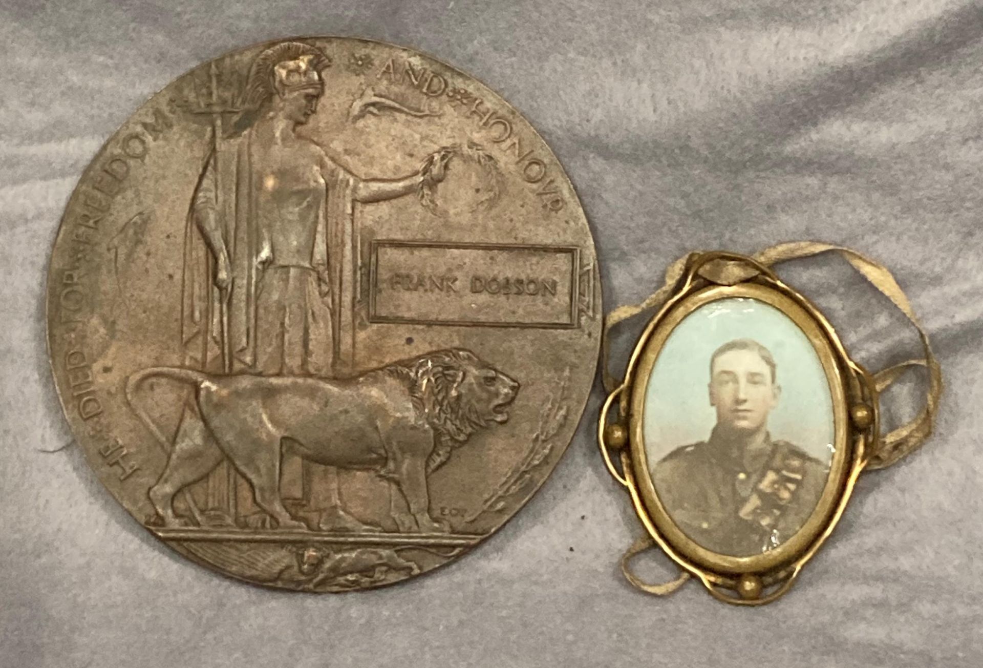 A bronze First World War death plaque to Frank Dobson together with a brass oval pendant with a