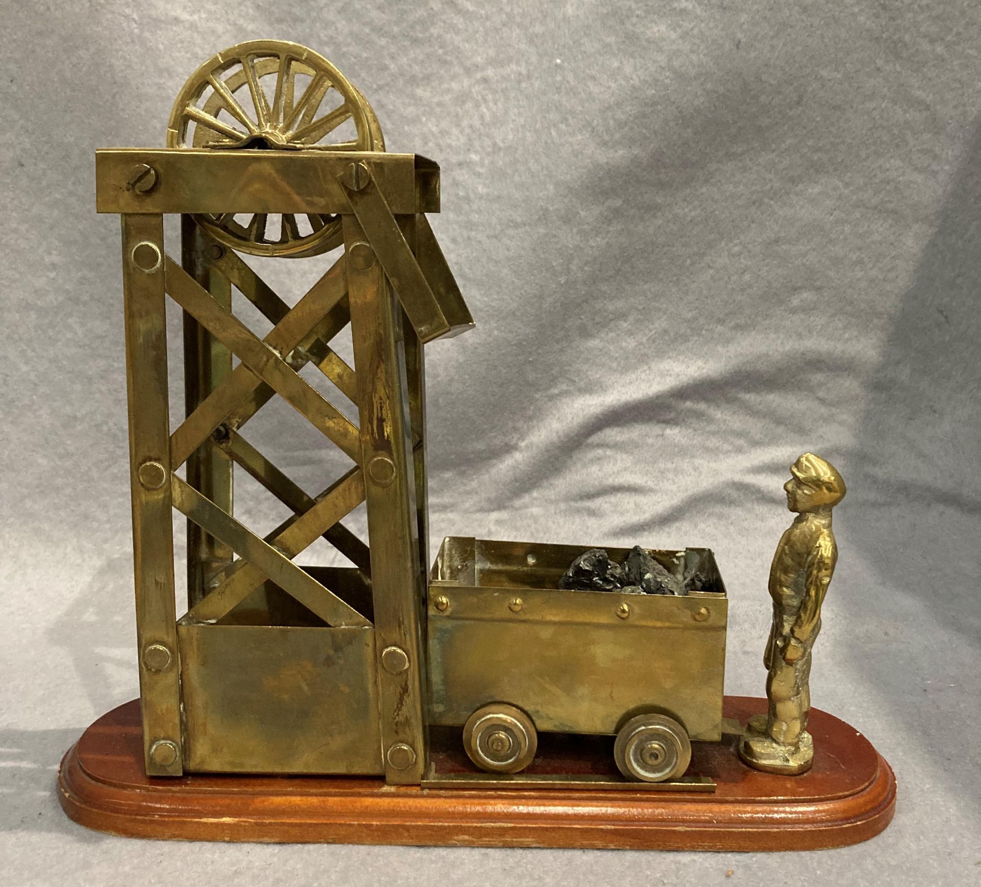 A brass mining model featuring a miner,