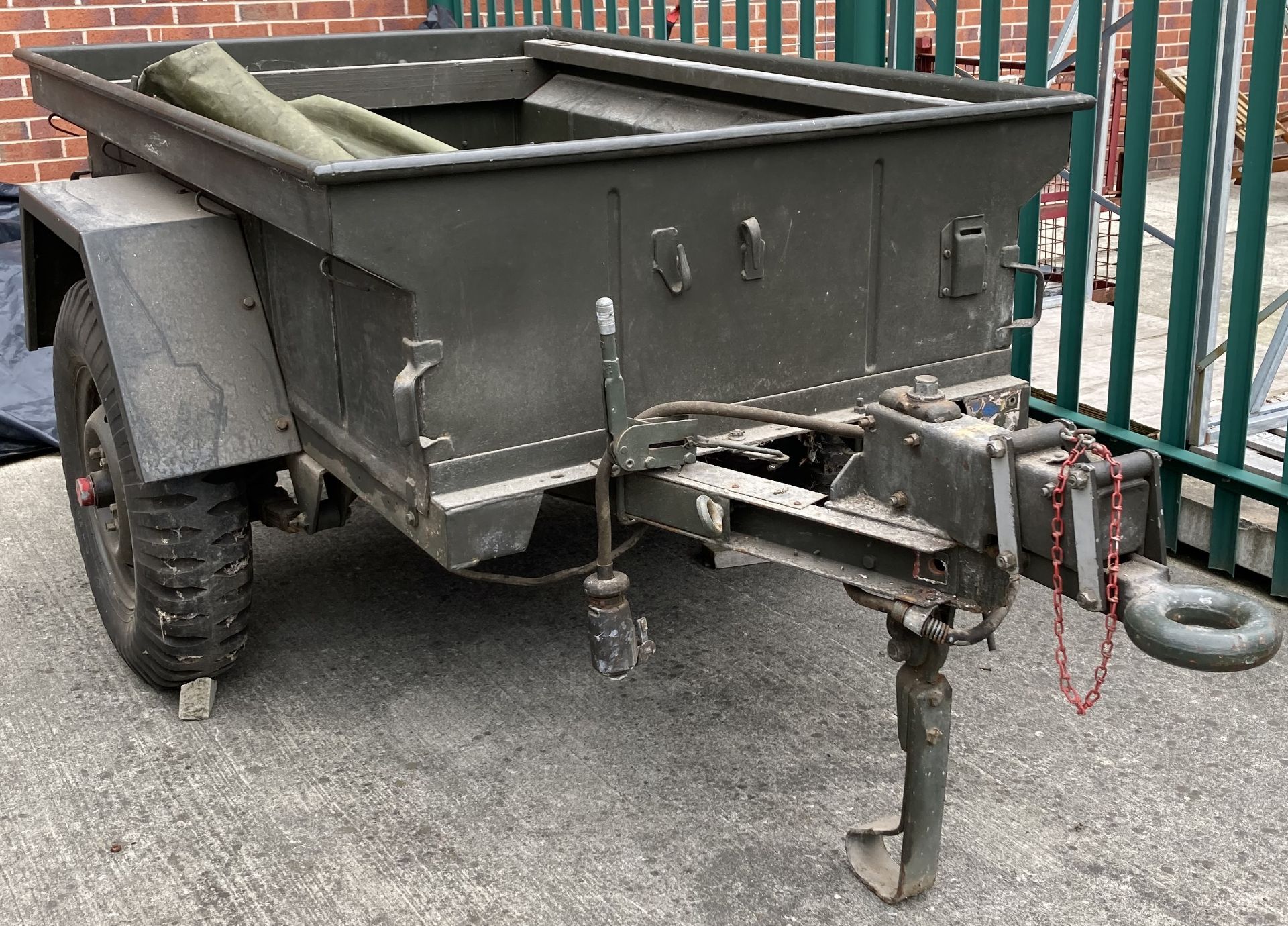 A military green metal single axle trailer, 130cm x 190cm x 147cm deep, complete with cover,