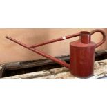 A large red metal watering can