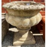 A pair of concrete and composition garden urns on pedestals each 30cm x 44cm high