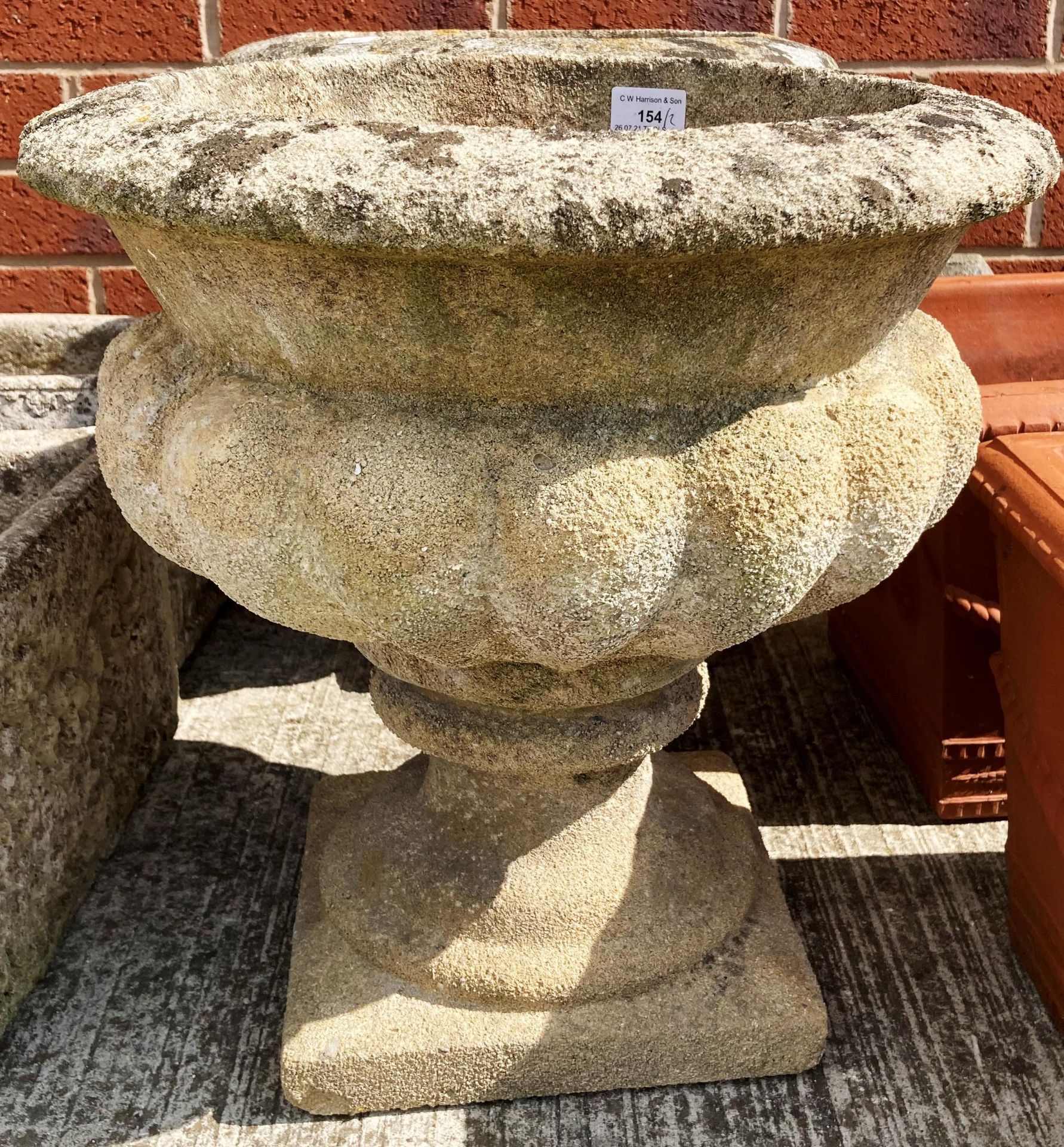 A pair of concrete and composition garden urns on pedestals each 30cm x 44cm high