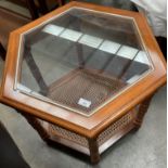 A medium wood finish octagonal coffee table with glass top and woven under tray 60cm