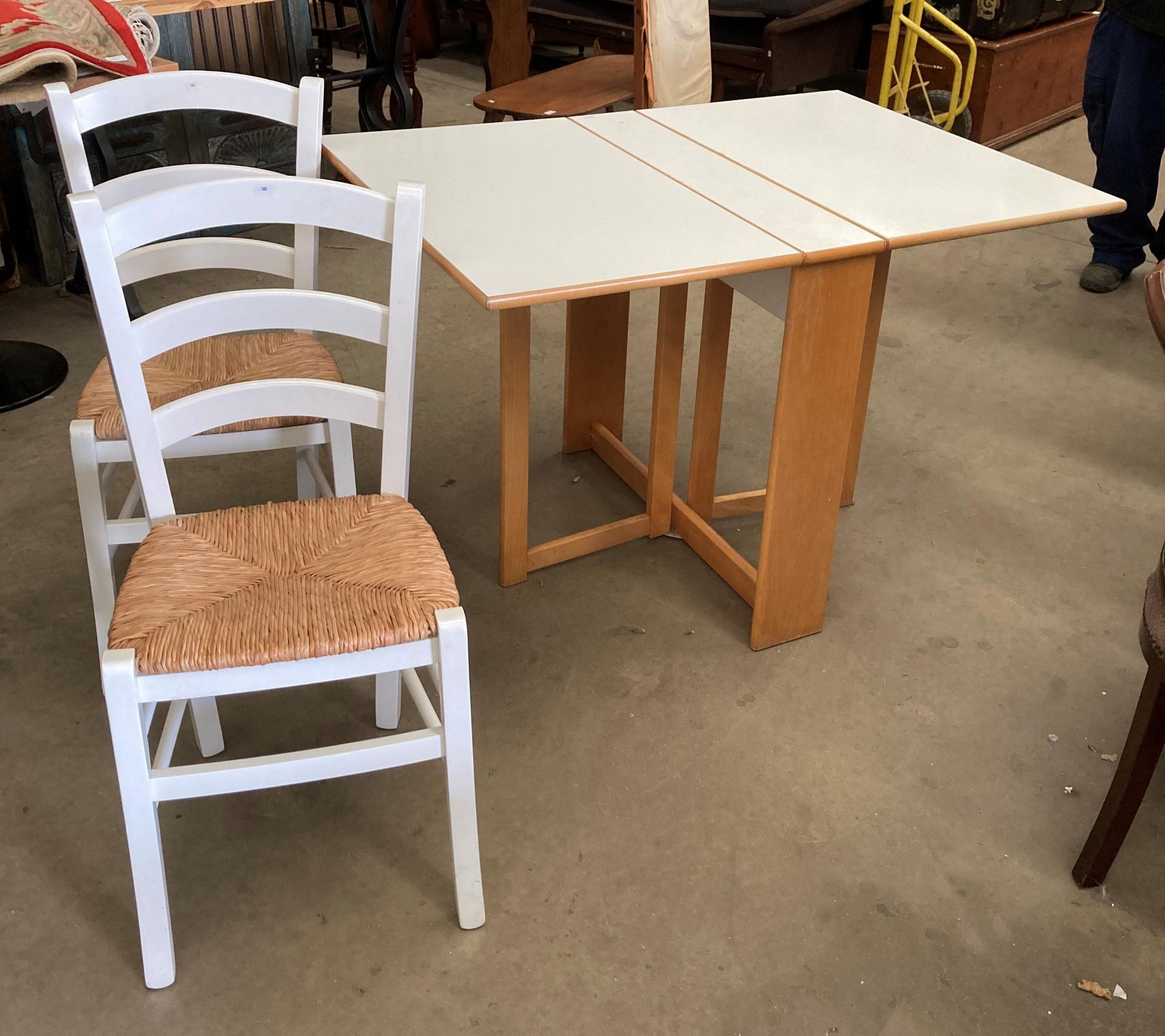 A white melamine drop leaf table 80 x 115cm when open and two white painted chairs with woven seats - Image 3 of 3