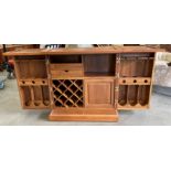 A home bar cabinet in medium finish hardwood made in Thailand - the doors open to reveal a fitted