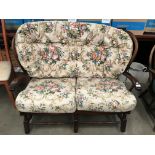 A mahogany stained cottage two seater with floral patterned seat and back pads [Please note - the