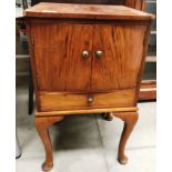 A mahogany sewing cabinet with lift top and two doors over single frieze drawer containing sewing