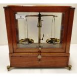 A set of small brass balance scales in a glazed wood framed case with under drawer - case size 28cm