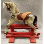 An old dapple grey composition rocking horse on red painted wooden frame, length approximately 80cm,