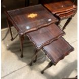A dark mahogany finish nest of three coffee tables with glass inserts
