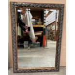 An ornate walnut and black finish framed wall mirror 104 x 75cm